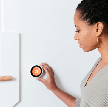 Woman changing temperature of smart thermostat