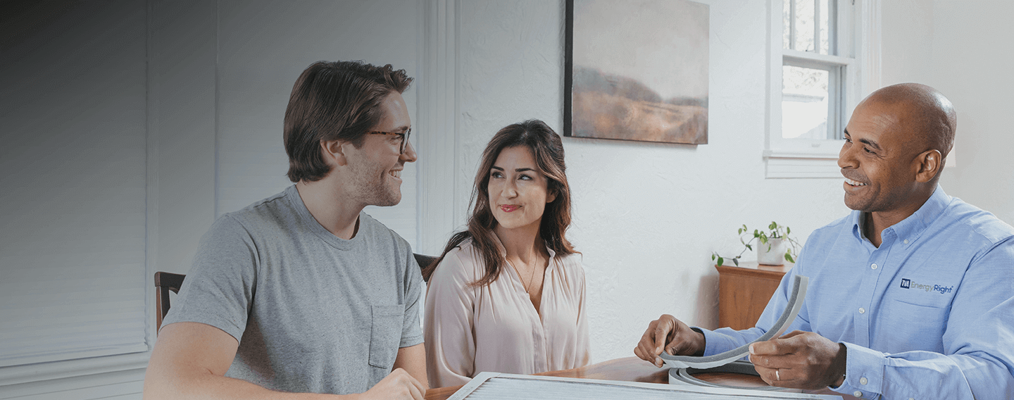 EnergyRight employee talking to couple at kitchen table, going over paperwork