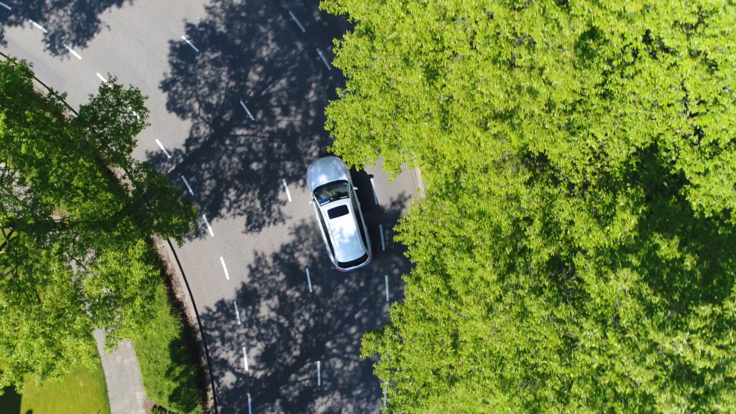 Drone picture overview of electric vehicle driving on road with trees