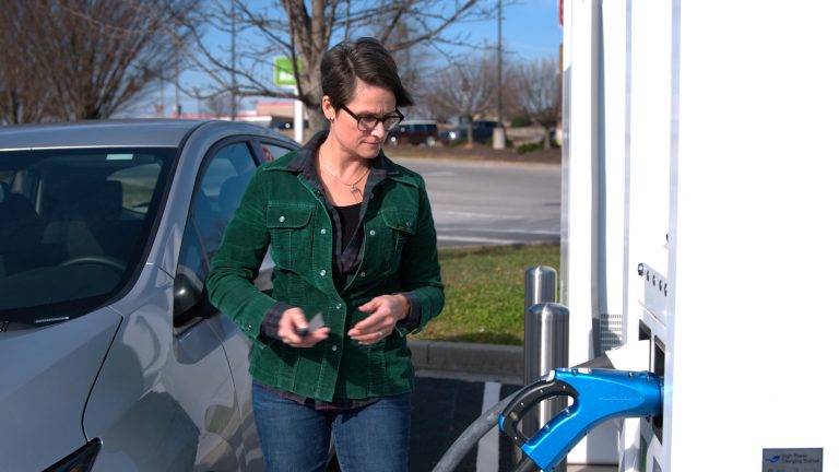 Woman charging an electric vehicle.