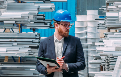 Business man in suit and hard hat with tablet in warehouse