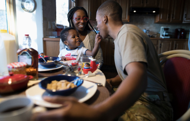 Family at table eating a meal and smiling