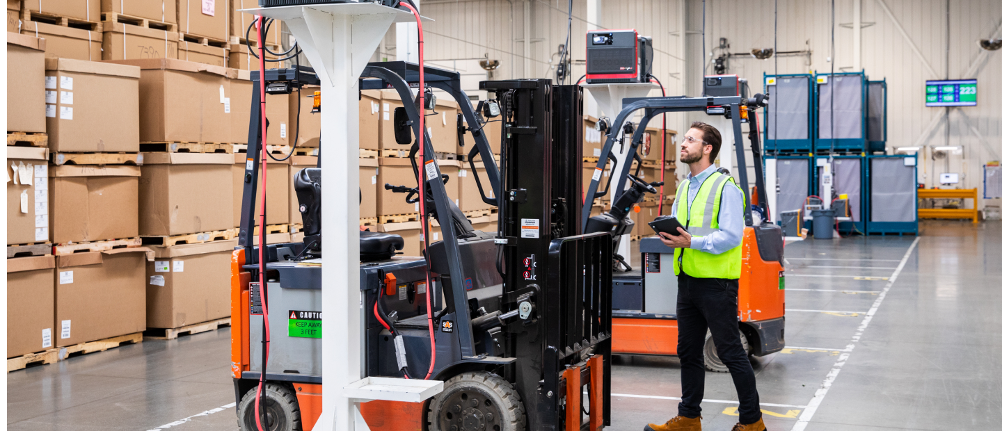 TVA employee examining electric forklift with tablet in hand