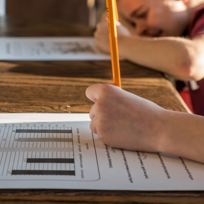 Close up of students completing homework, cropped in on hand filling out worksheet