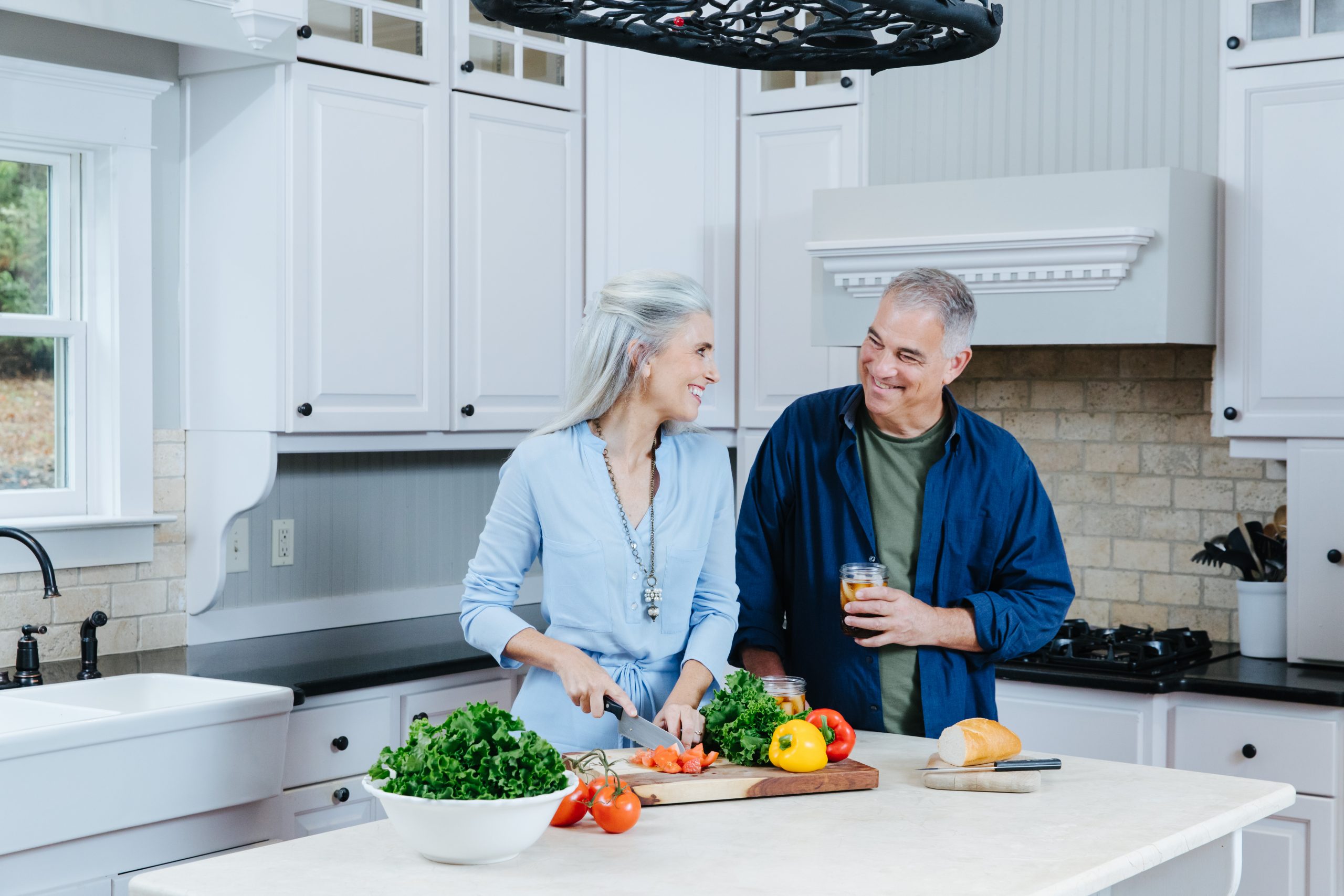 Older couple in kitchen cooking and smiling at each other