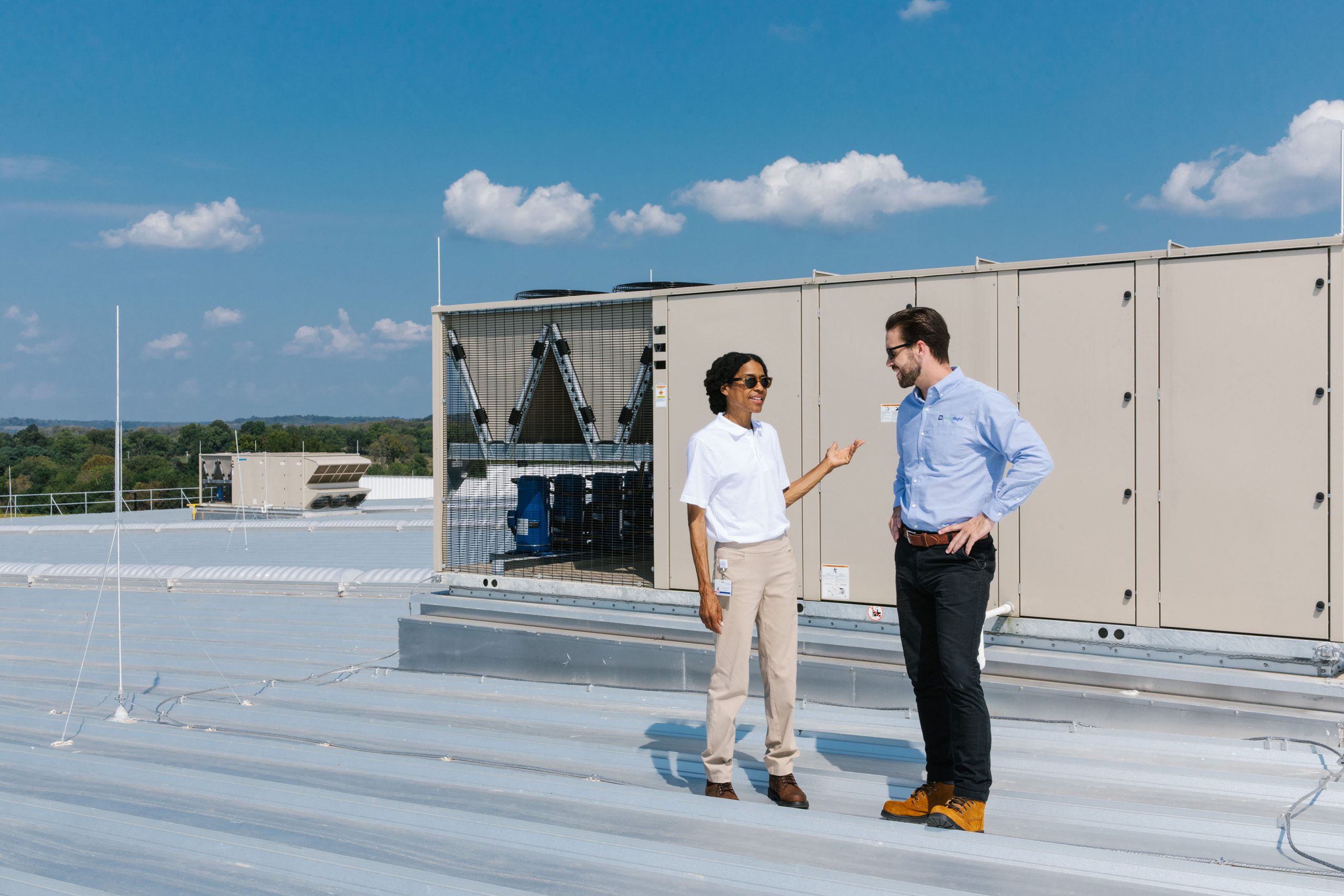 man and woman talking outside in front of industrial HVAC unit