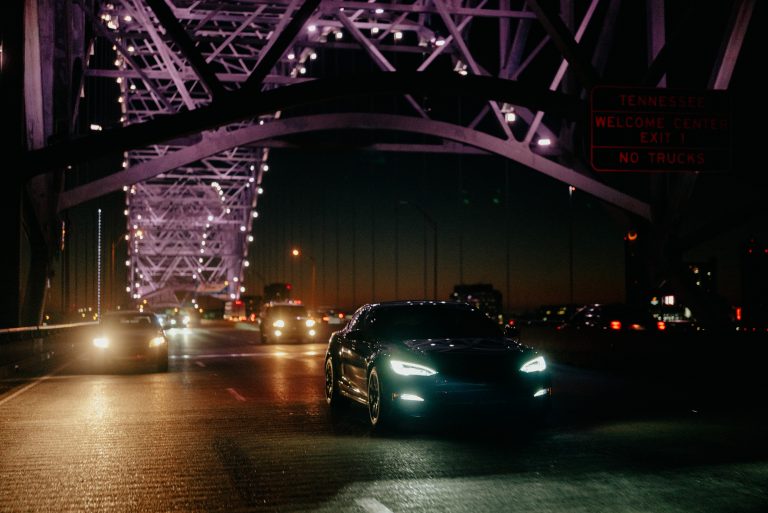 EV driving at night over lit up bridge
