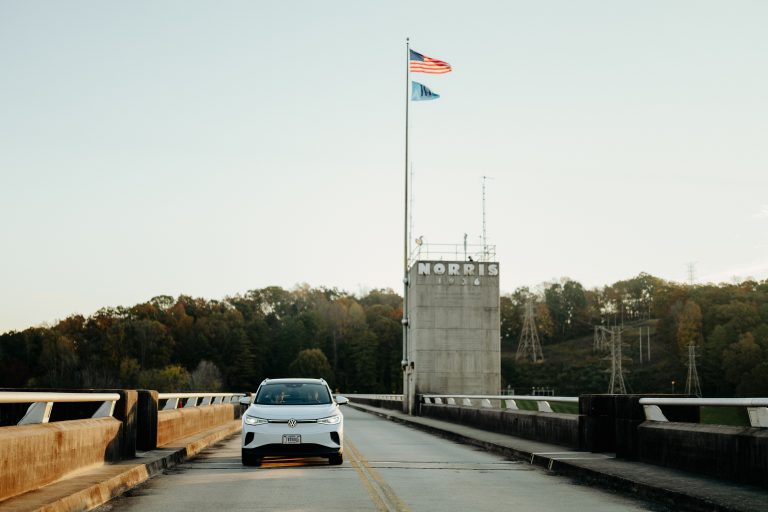 Electric vehicle driving over dam with US flag in the background