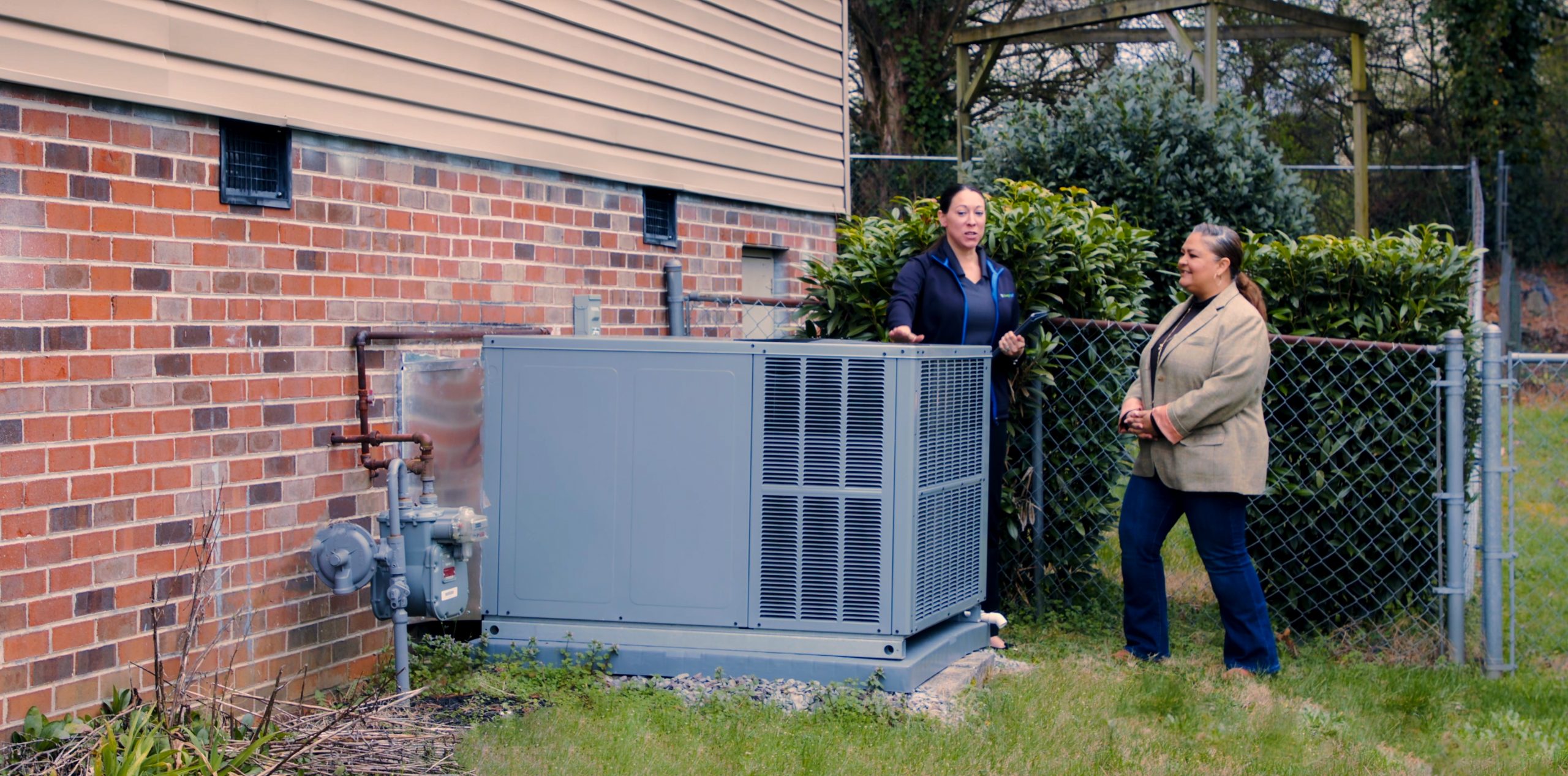 TVA employee and homeowner talking outside by HVAC unit