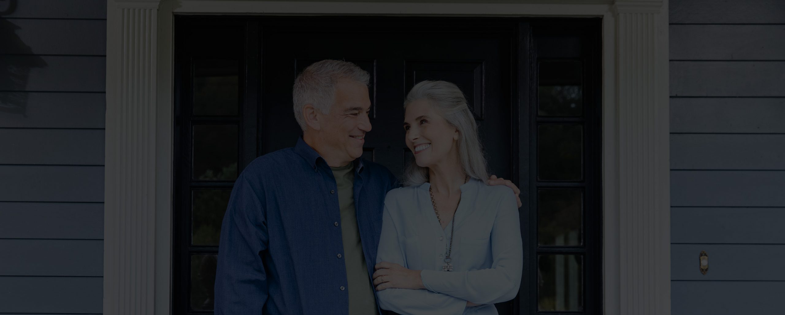 Older couple smiling at each other in front door of house