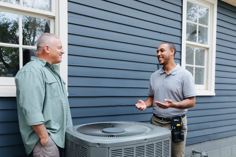 Contractor and home owner talking outside next to HVAC unit