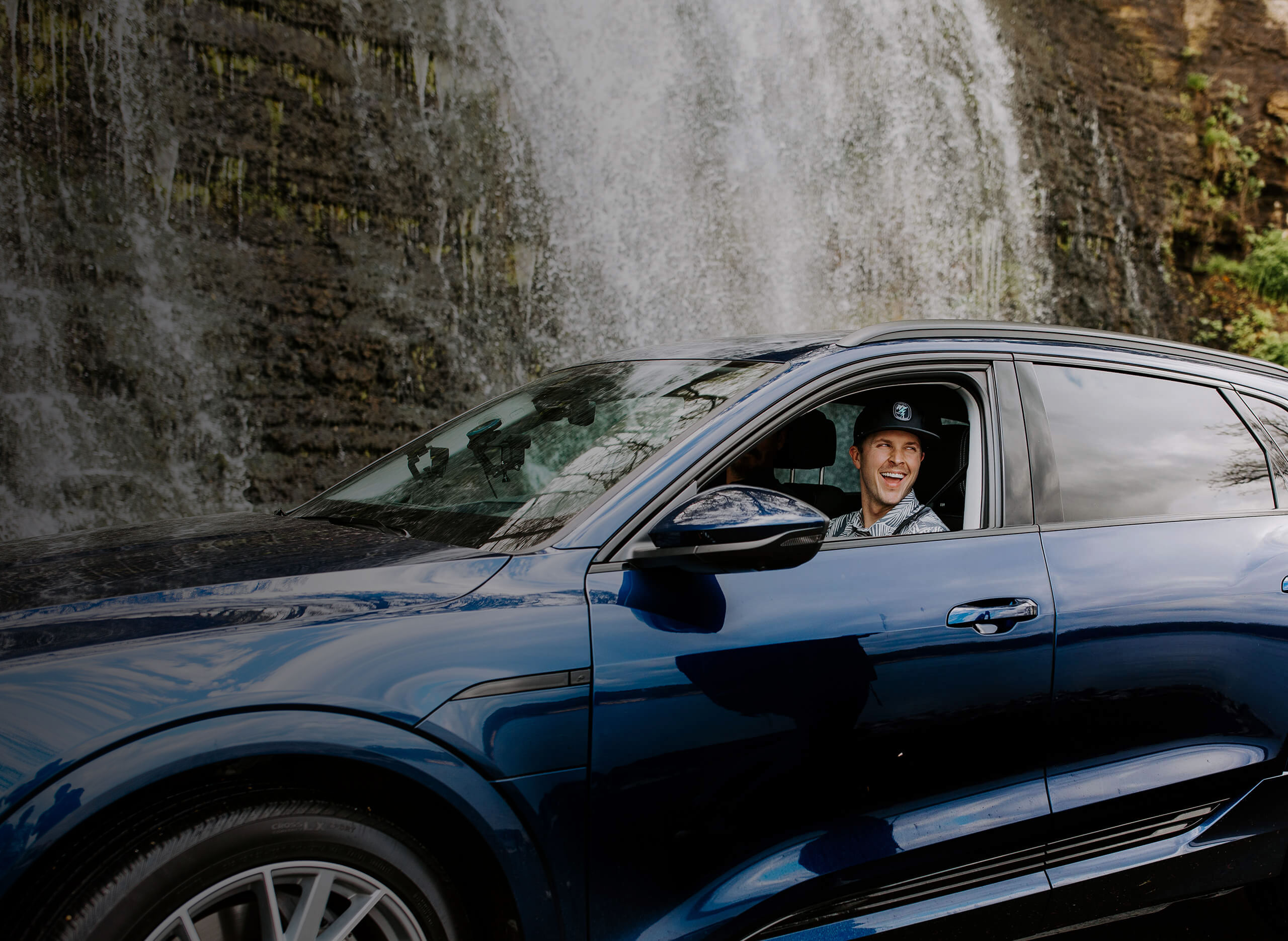 Trevor Bayne driving electric vehicle with waterfall in the background