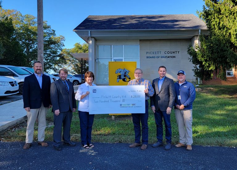 Group of people outside holding oversized check