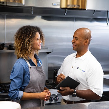 TVA employee with tablet talking to chef business owner in kitchen