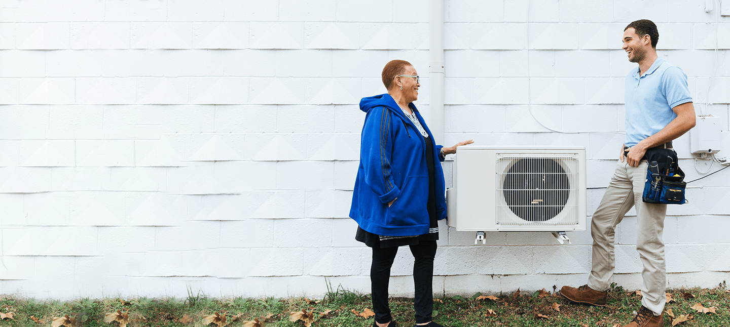 Contractor talking to homeowner outside by her HVAC unit