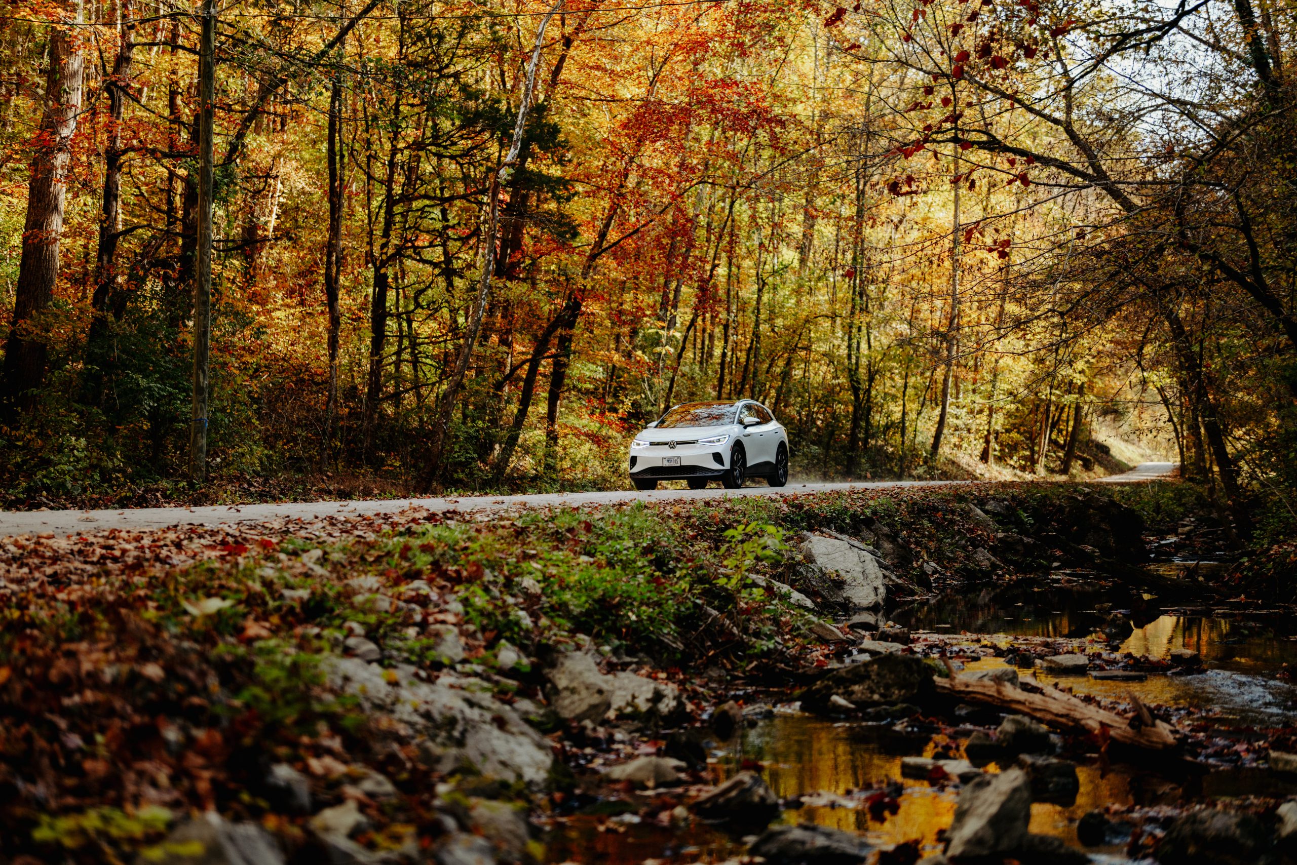 Electric vehicle driving through fall landscape