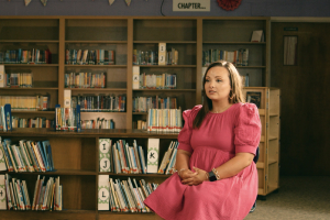 woman in pink dress sits in school library