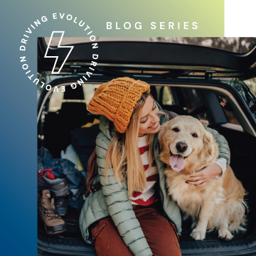 Woman sitting in back of an EV with the hatch up, hugging her golden retriever.