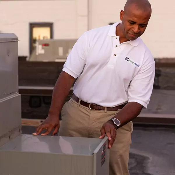 Man in TVA polo shirt outside looking at HVAC unit