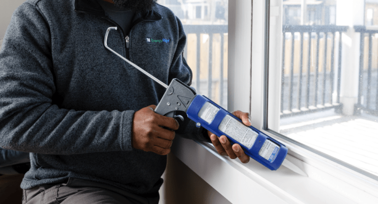 Man applies sealant around a window.