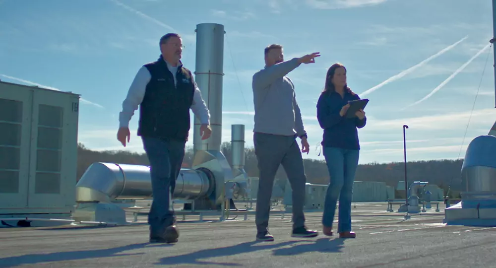 Three people inspecting a commercial HVAC system.