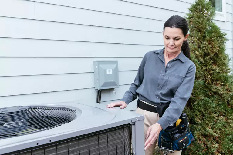 Woman inspecting HVAC unit.