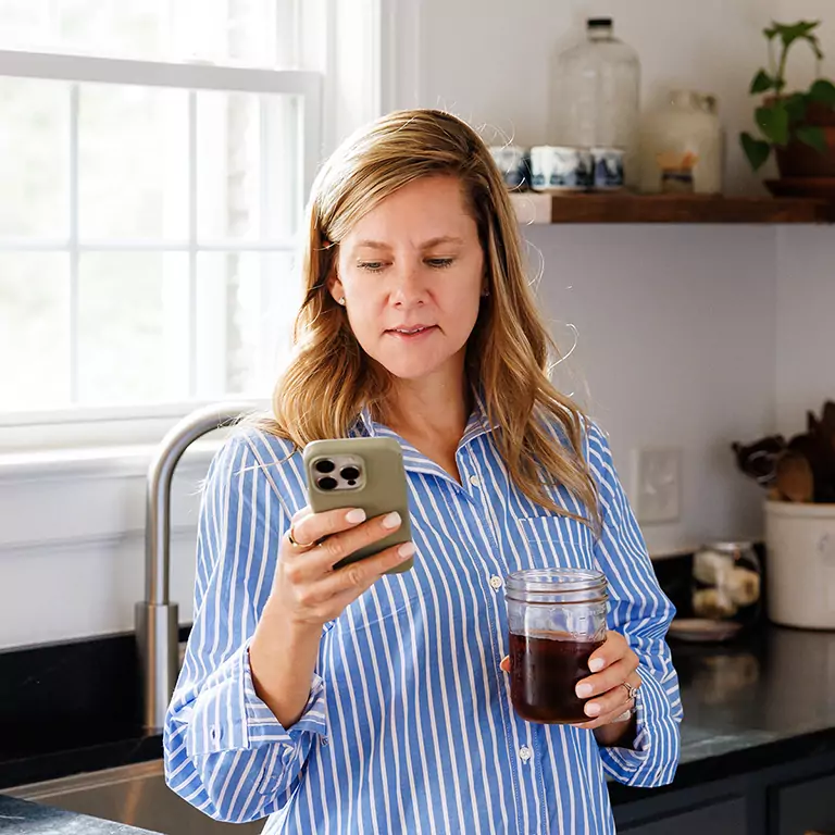 Woman checking her thermostat app in her kitchen