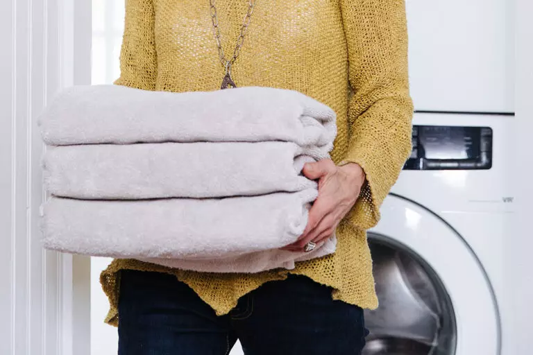 Woman removing towels from an energy efficient dryer.
