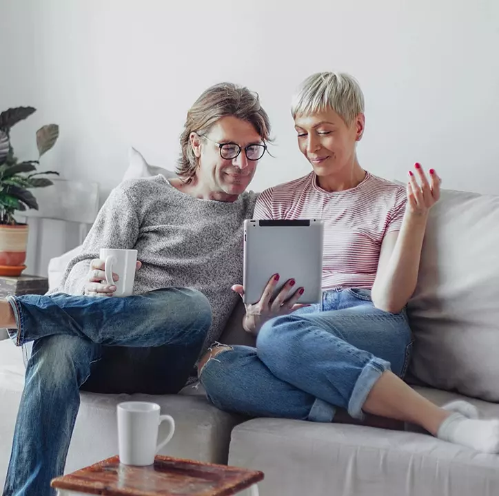 Couple reading tablet on couch.