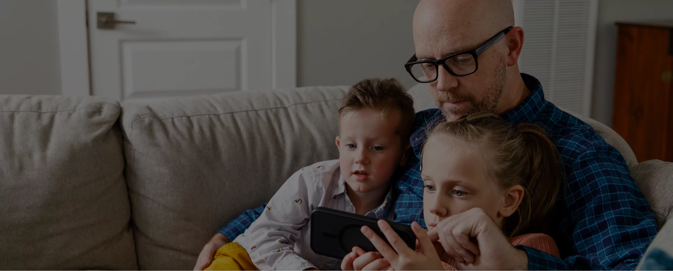 Father and kids on a couch, looking at a tablet and signing up for Green Switch.