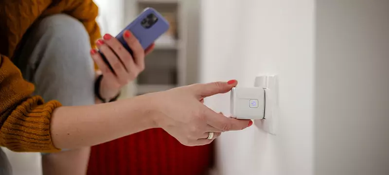 Close-up of a woman's hand plugging in a wi-fi enabled smart plug.
