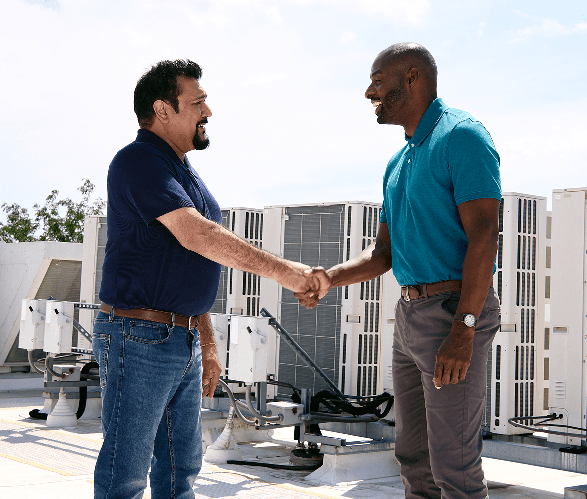 TVA EnergyRight Advisor and customer shaking hands on a business's roof in front of HVAC units.