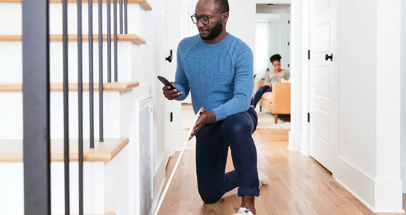 Man wearing a blue sweater, installing a new air filter. 