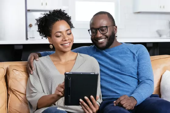 Couple sitting on a couch reviewing information on a tablet together