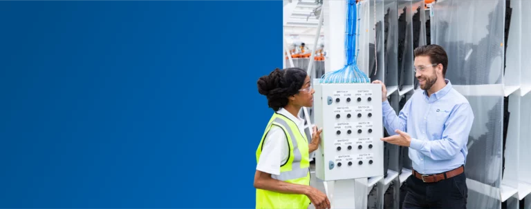 A TVA Energy Expert explains an industrial control panel with switches to another expert, demonstrating operational efficiency at a facility.