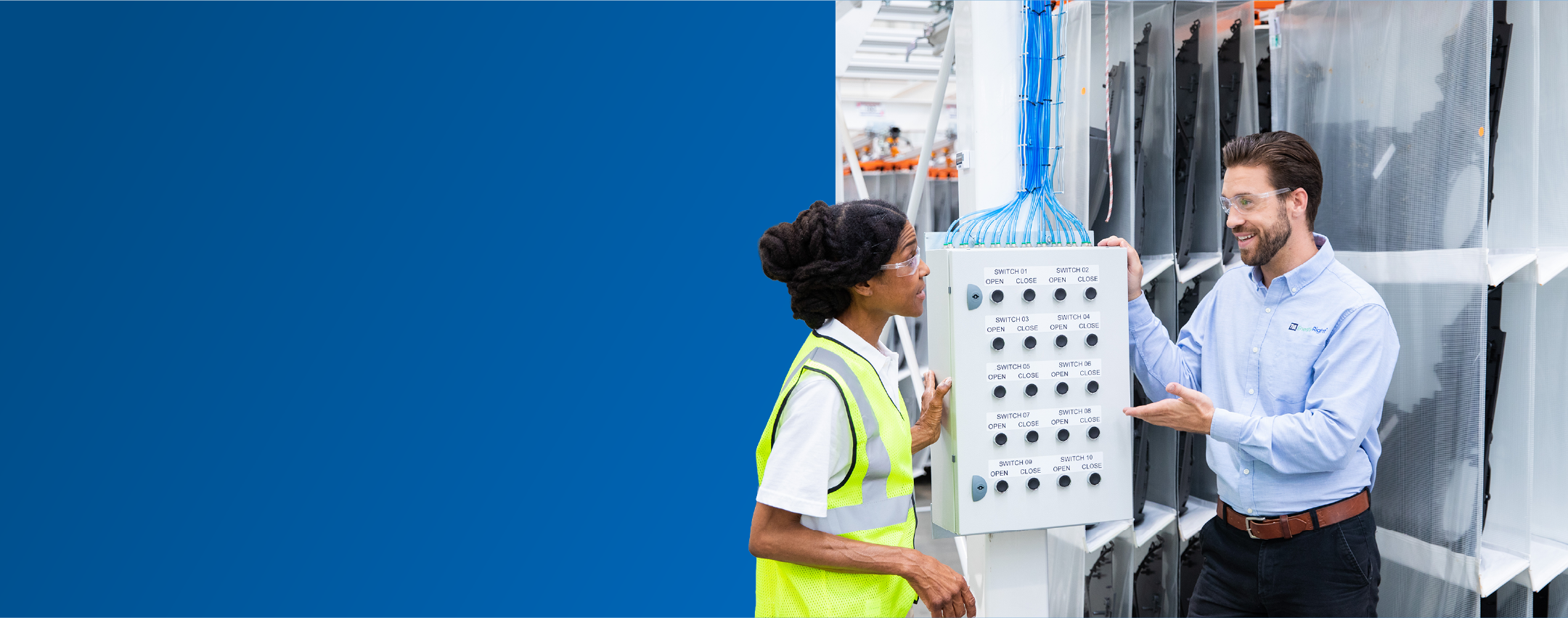 A TVA Energy Expert explains an industrial control panel with switches to another expert, demonstrating operational efficiency at a facility.