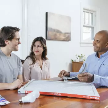 Technician reviewing documents with homeowners at a table during a home consultation