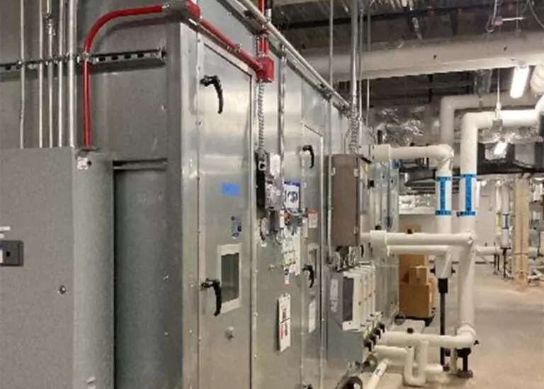 A large, high-efficiency commercial HVAC air handling unit at Methodist University Hospital with galvanized steel panels and insulated piping systems inside a mechanical room.