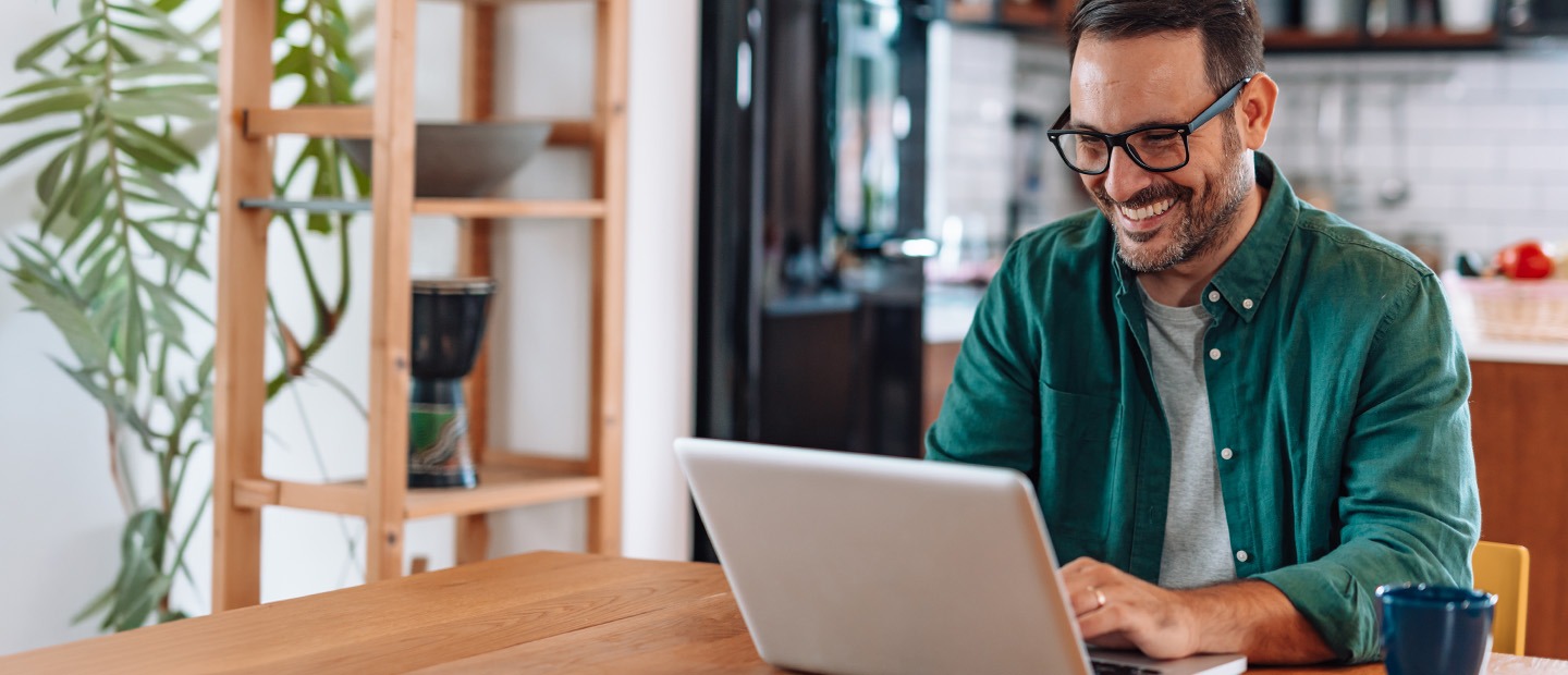 Smiling homeowner on laptop, engaging with EnergyRight online resources for energy-efficient home solutions.