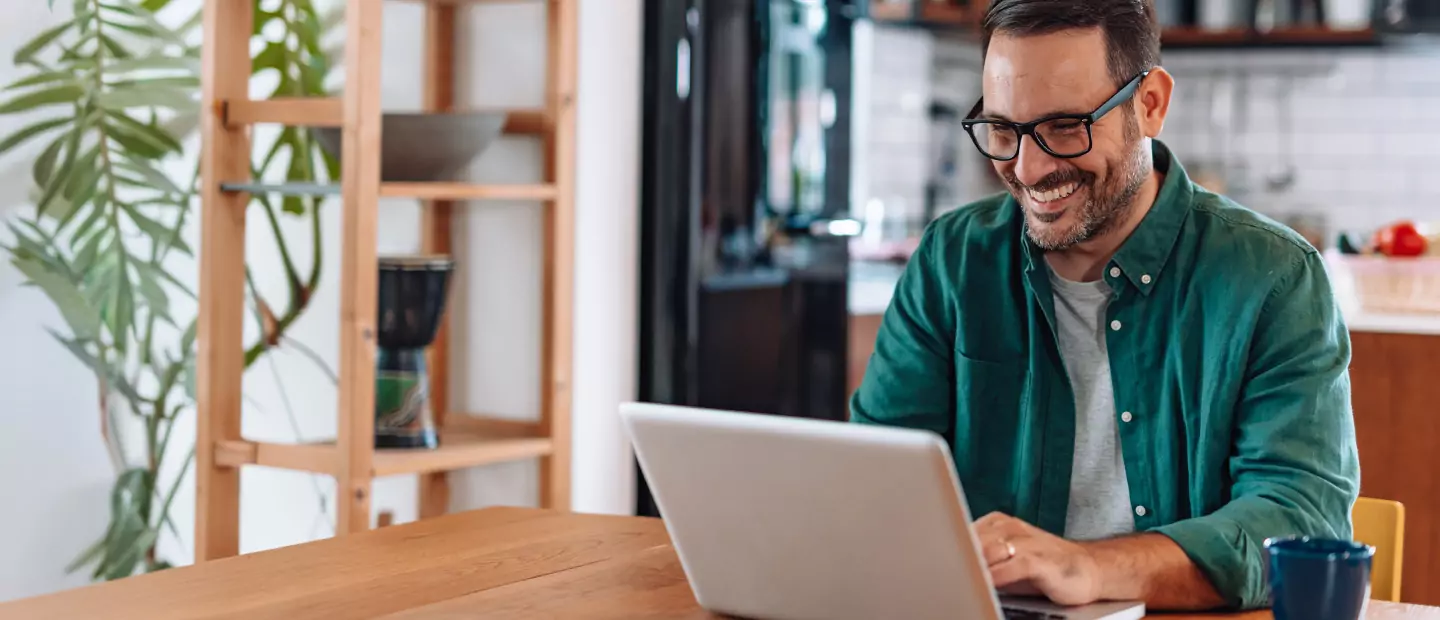 Smiling homeowner on laptop, engaging with EnergyRight online resources for energy-efficient home solutions.