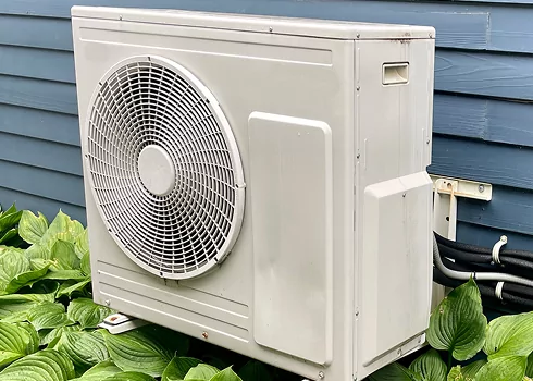 Modern outdoor heat pump unit installed at a home, promoting energy efficiency for year-round comfort and savings.