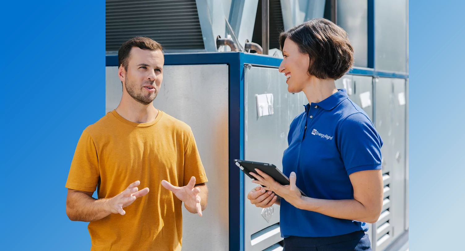 A man consults with a TVA Energy Expert holding a tablet about energy efficiency solutions for a large commercial heat pump system.