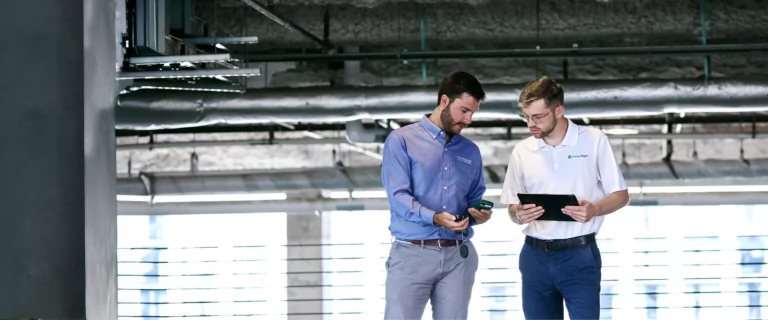 Two TVA Energy Experts use a handheld device and tablet to assess energy solutions in a building.