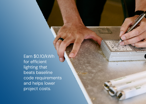 A technician uses a pen to note specifications on a lighting ballast fixture next to linear lamp tubes. Text overlay reads: Earn $0.10/kWh on installed building-wide Lighting Power Density and reduce upgrade costs.