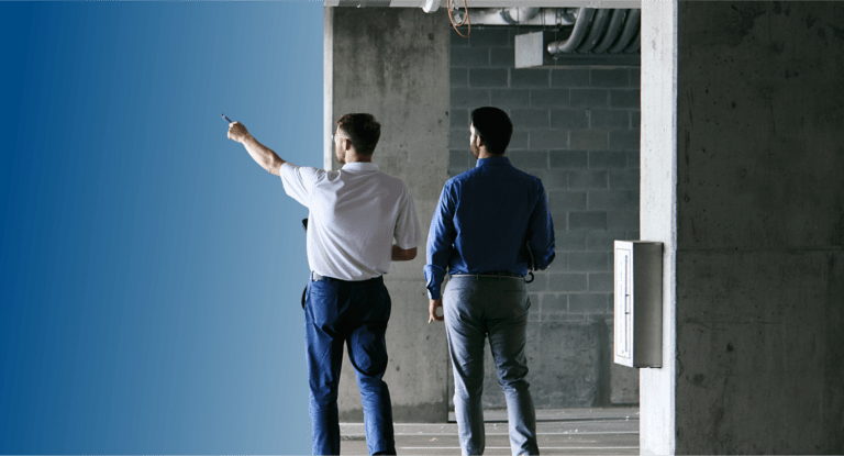 Two TVA Energy Experts assess an unfinished commercial site, one pointing towards potential energy-efficient upgrades.