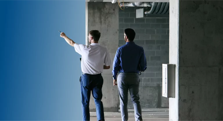 Two TVA Energy Experts assess an unfinished commercial site, one pointing towards potential energy-efficient upgrades.