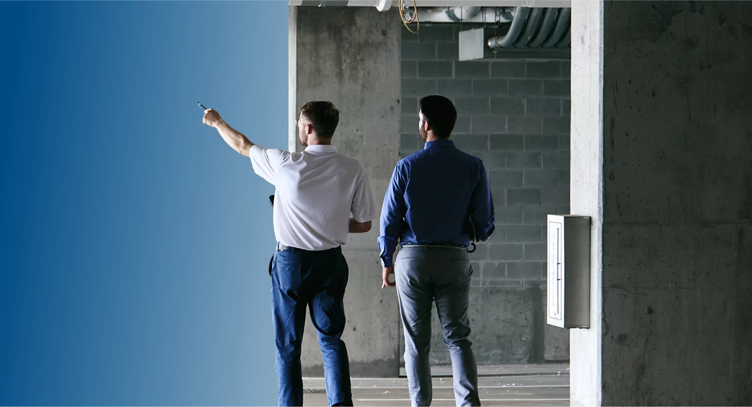 Two TVA Energy Experts assess an unfinished commercial site, one pointing towards potential energy-efficient upgrades.