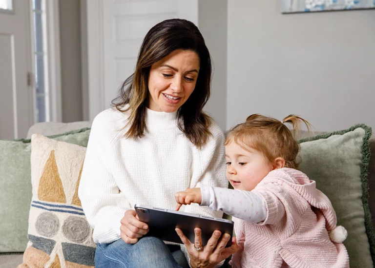 A smiling TVA Energy Expert helps a child learn about energy solutions on a tablet, promoting home energy efficiency.