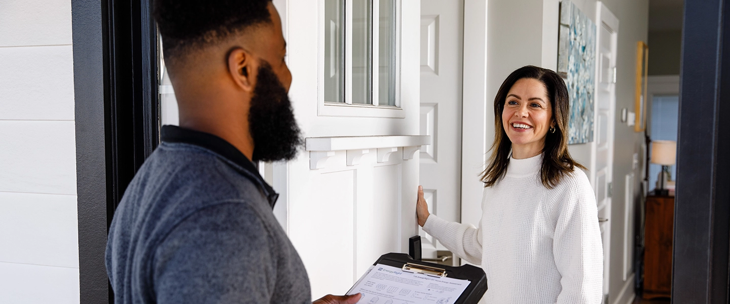 A TVA Energy Expert discusses home energy efficiency with a smiling customer during an EnergyRight assessment at her doorway.