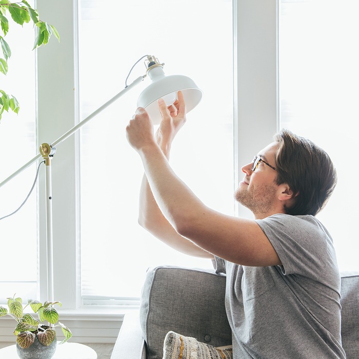 TVA Energy Expert installing an energy-efficient LED bulb into a floor lamp for home energy savings.